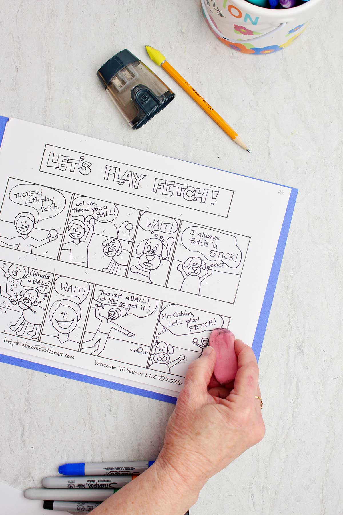 A person erasing pencil lines on a pen and ink comic book strip about a boy and his dog.