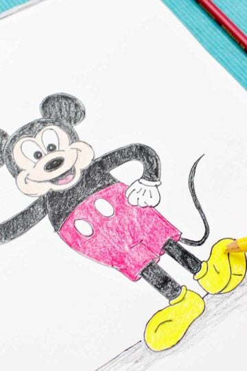 A person coloring in Mickey's shoes with a yellow colored pencil.