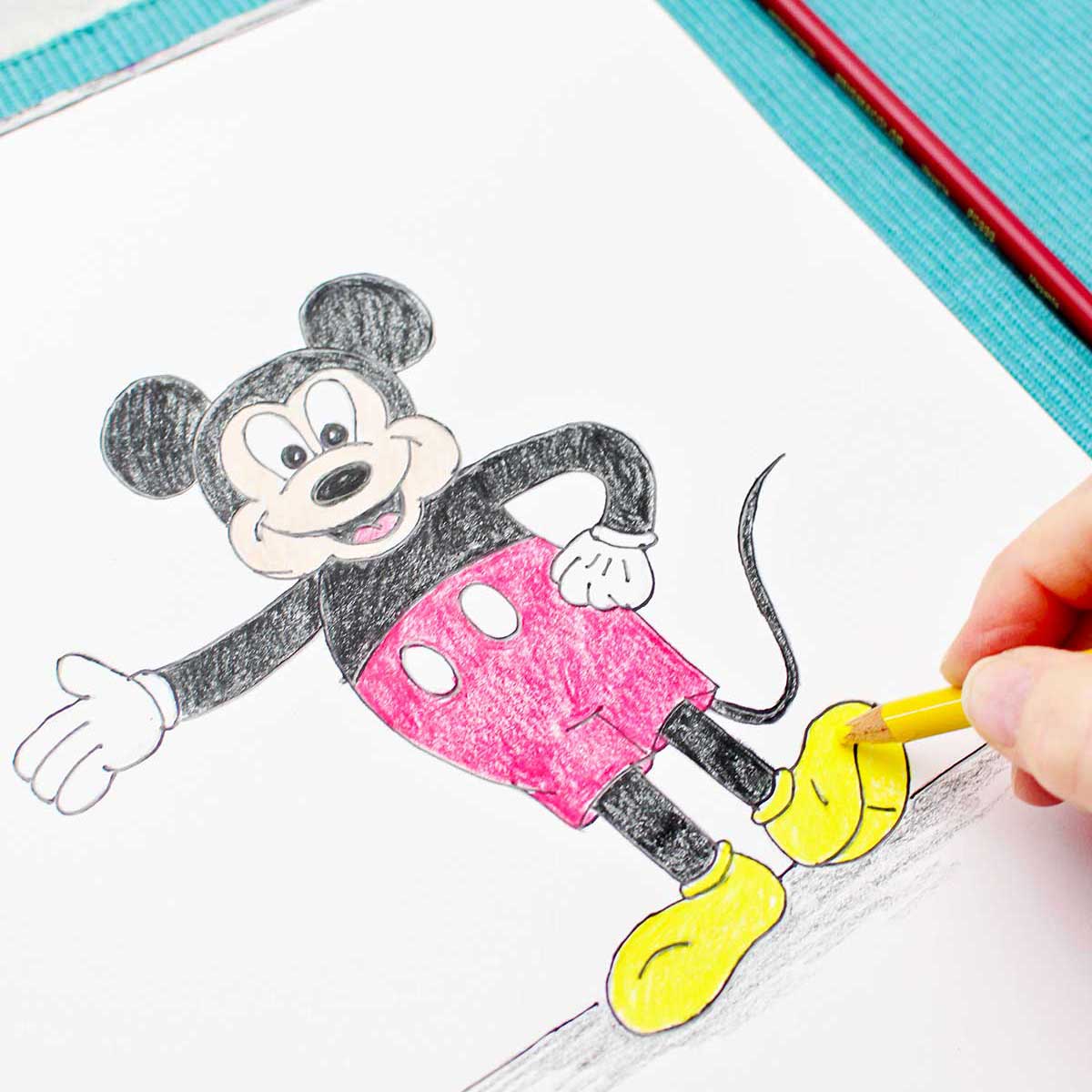 A person coloring in Mickey's shoes with a yellow colored pencil.