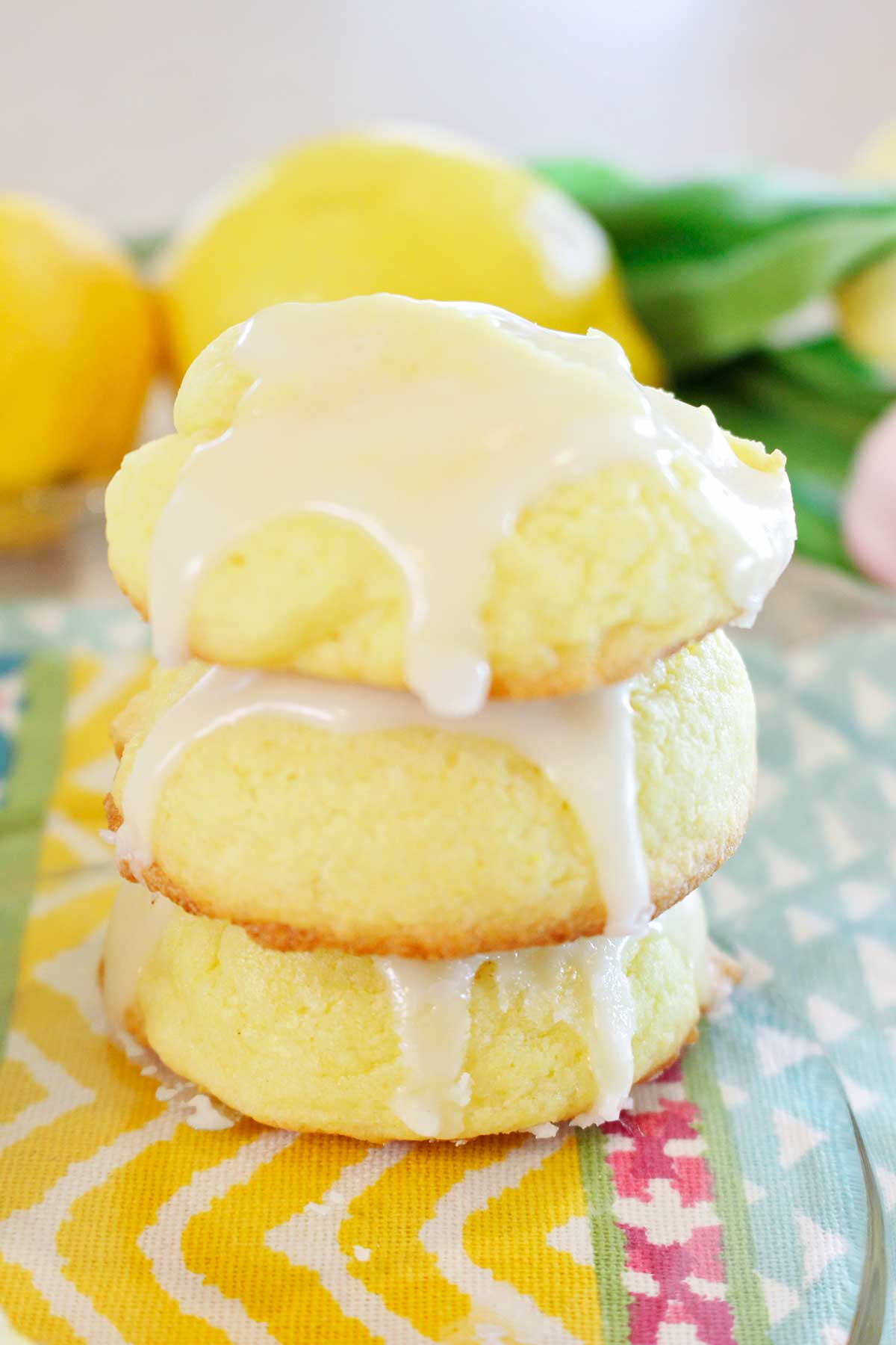 A stack of three lemon cake cookies on a colorful placemat.