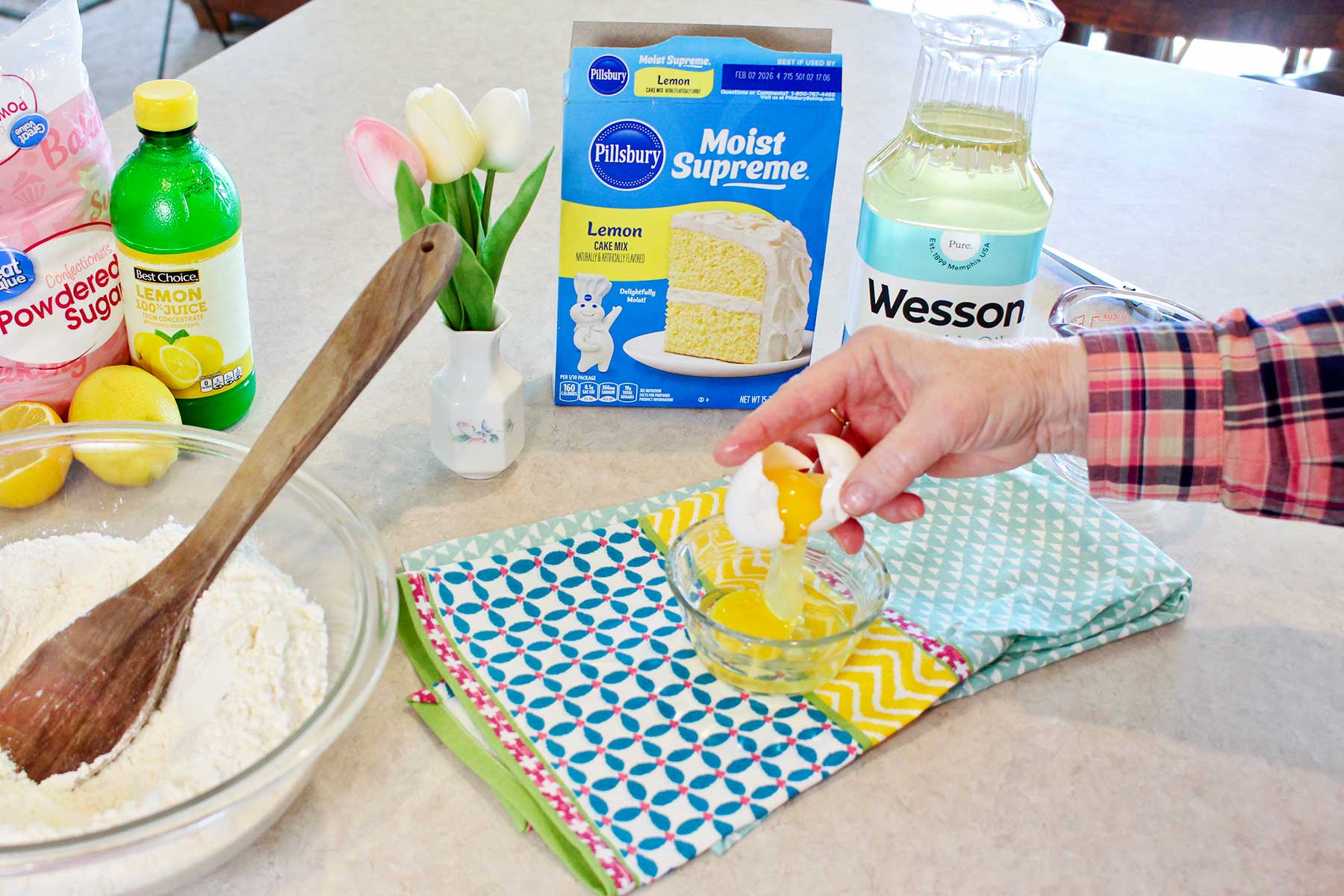 A person cracking an egg in a small glass bowl for the cake mix cookies.