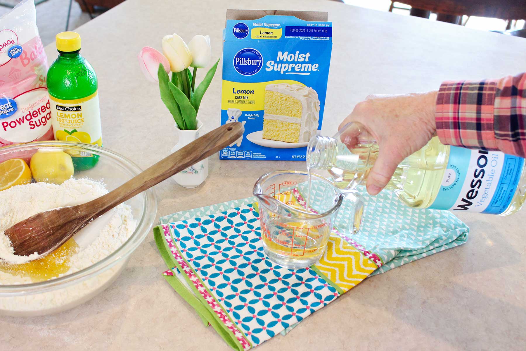 A person measuring out vegetable oil for cake mix cookies.