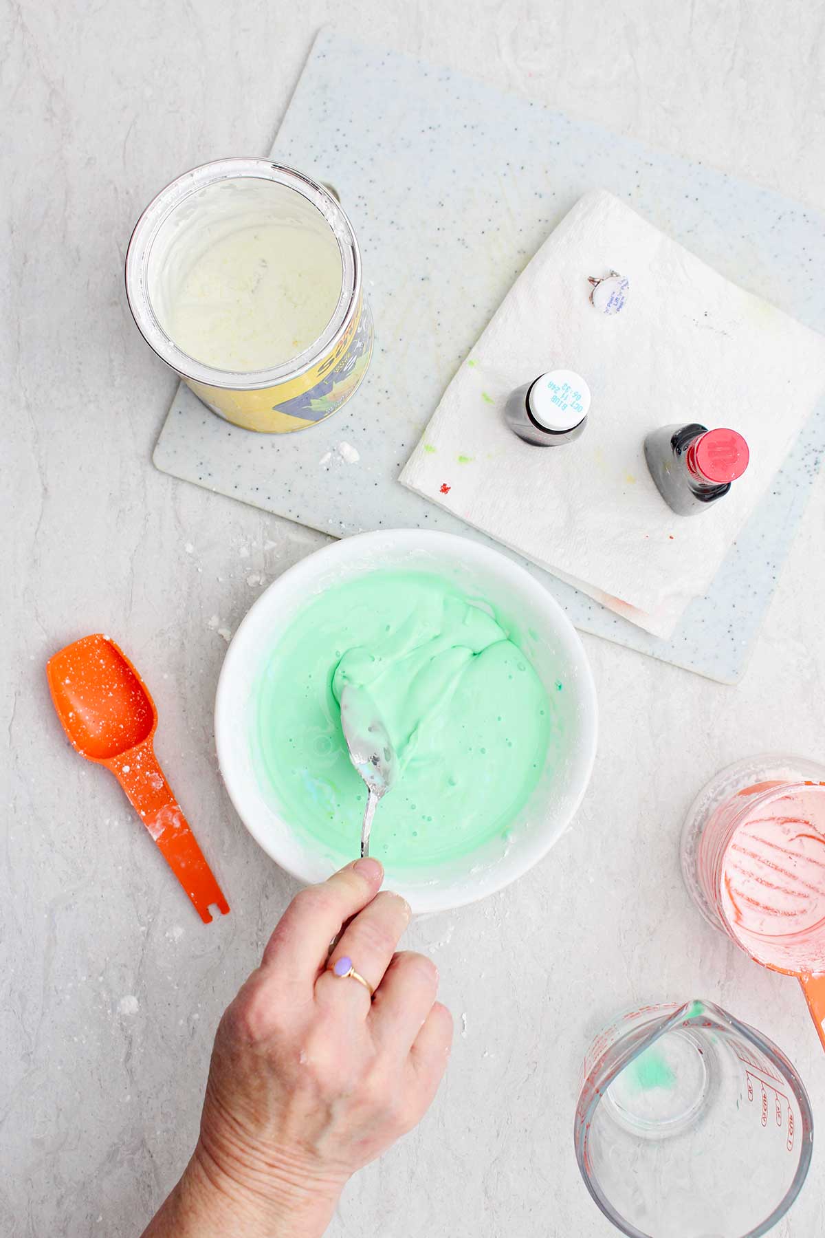 A person mixing a light green bowl of oobleck ingredients.