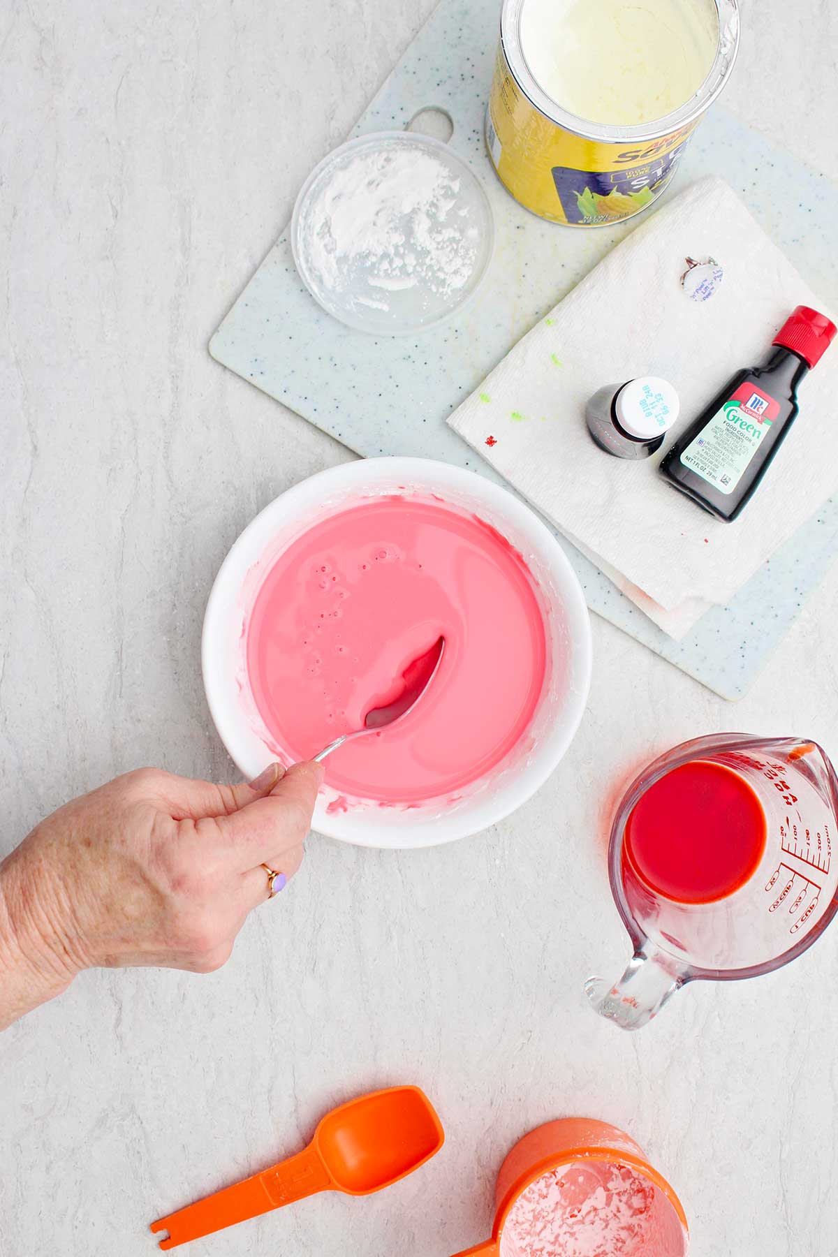 A person mixing a bowl of pink oobleck ingredients.