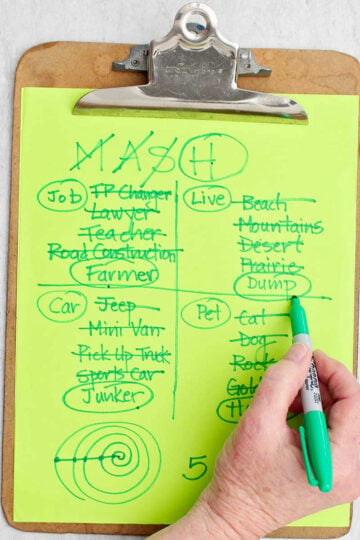 A person circling the living location of "dump" with green sharpie on a MASH game.