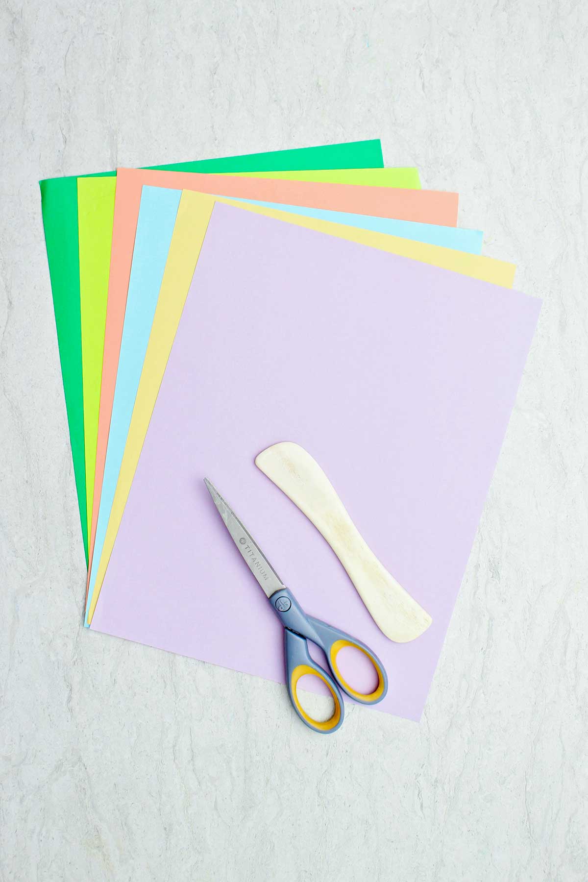 Colorful paper, a wooden bone folder and scissors.