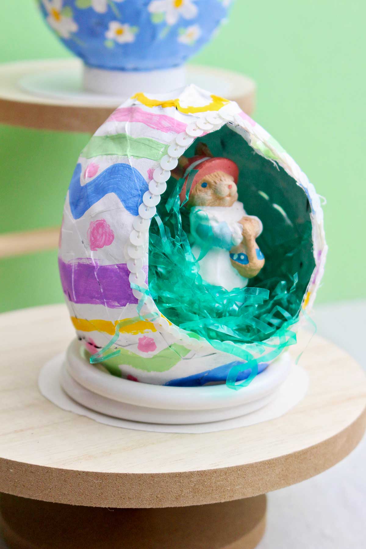 A hollowed out easter egg paper mache project with a small bunny inside.