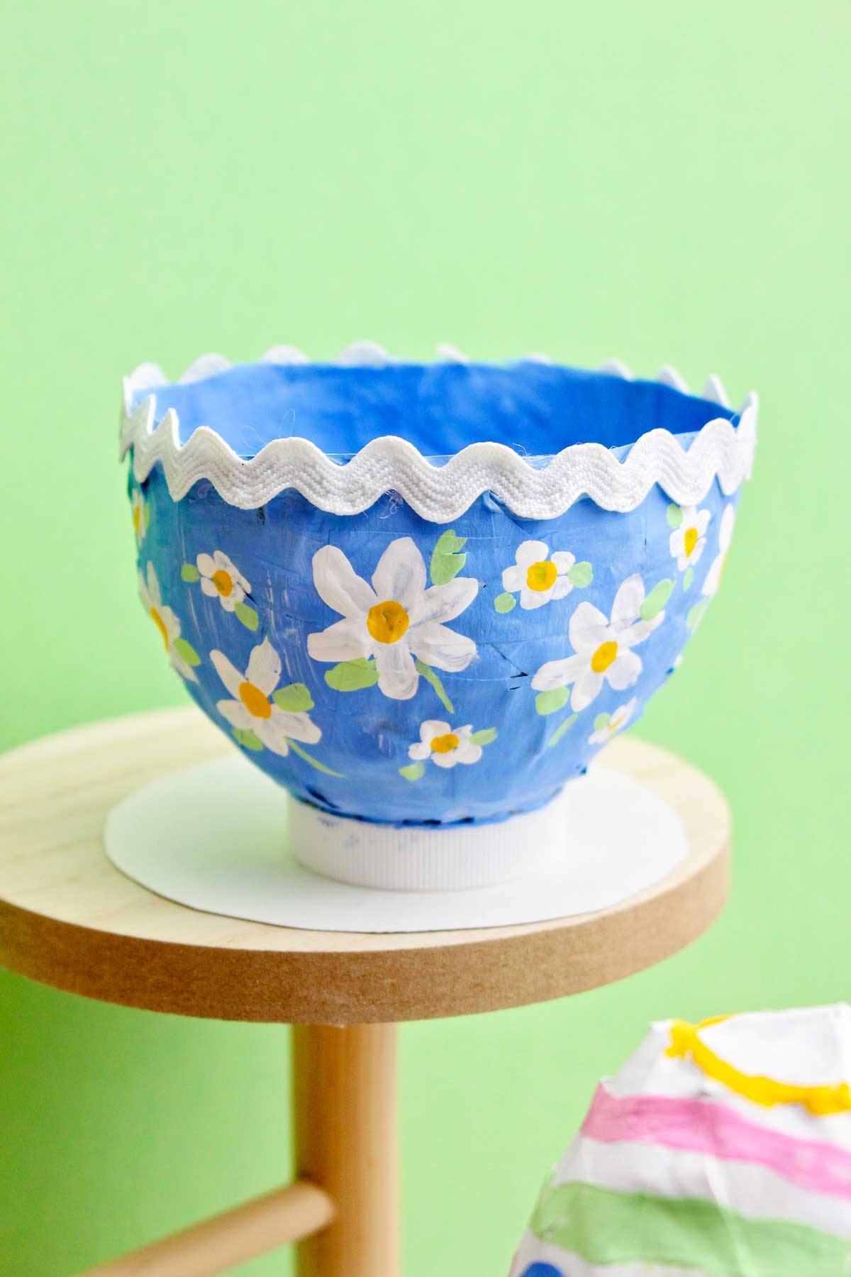A cute blue paper mache bowl with flowers painted on and a rick rack boarder.