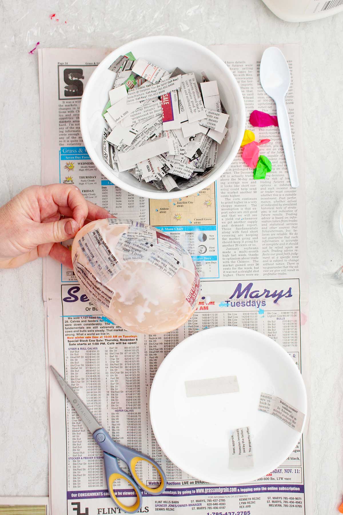A person holding a small balloon being used as a mold for a paper mache project.