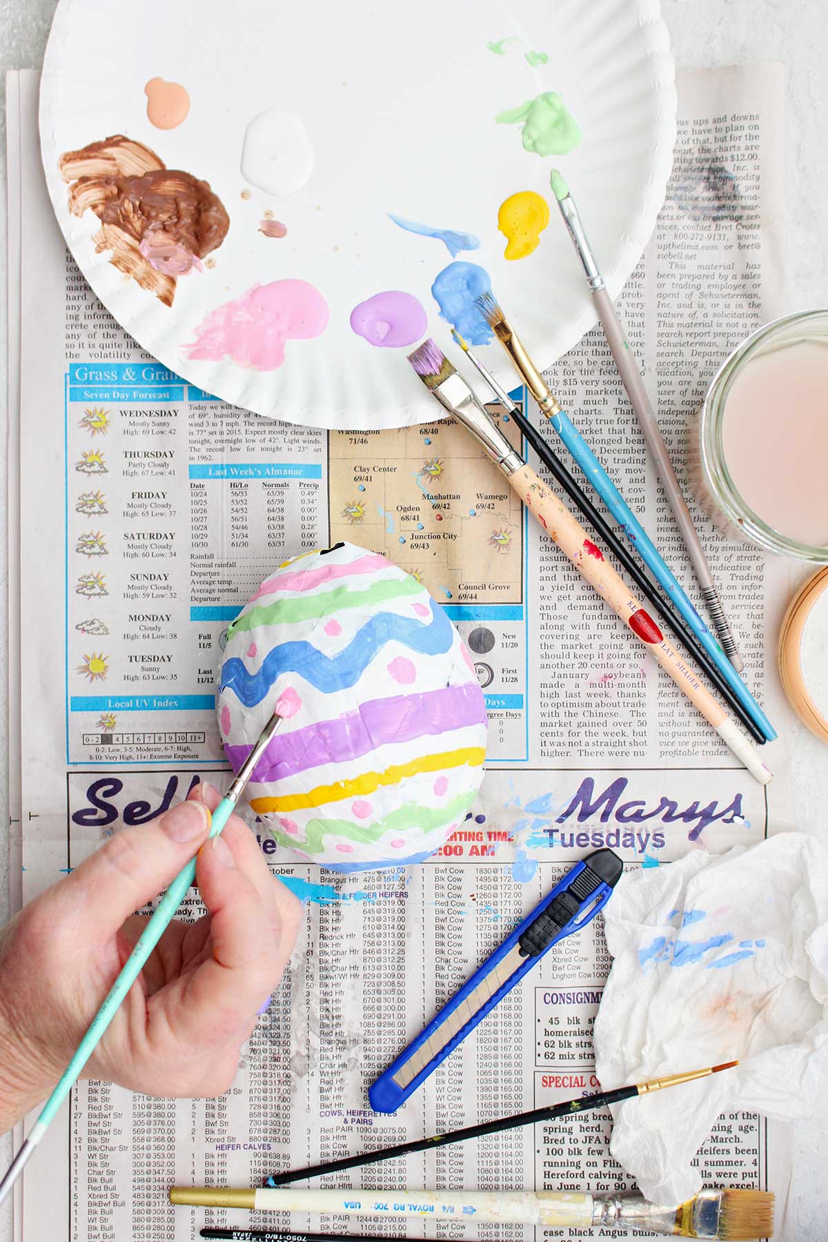 A person painting a paper mache easter egg.