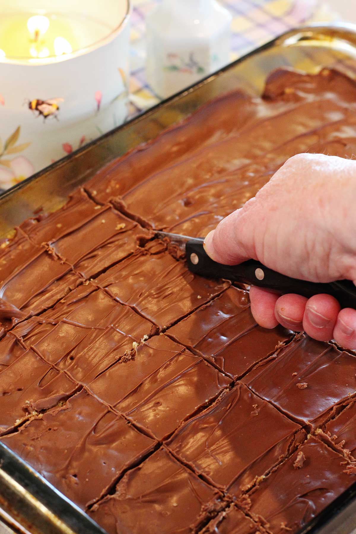 A person cutting a 9x13 pan of scotcharoos into servings.