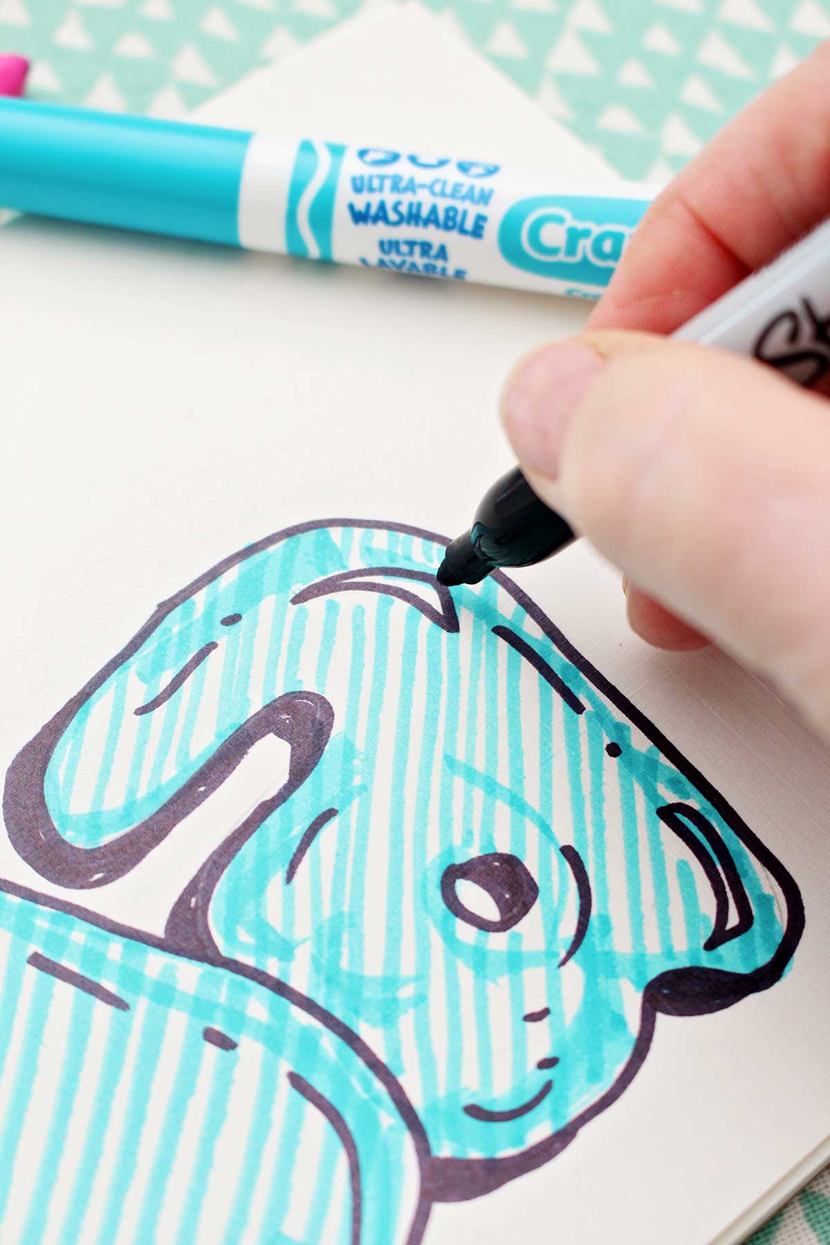 A close up of a person adding detail to a colored in bubble letter "a".