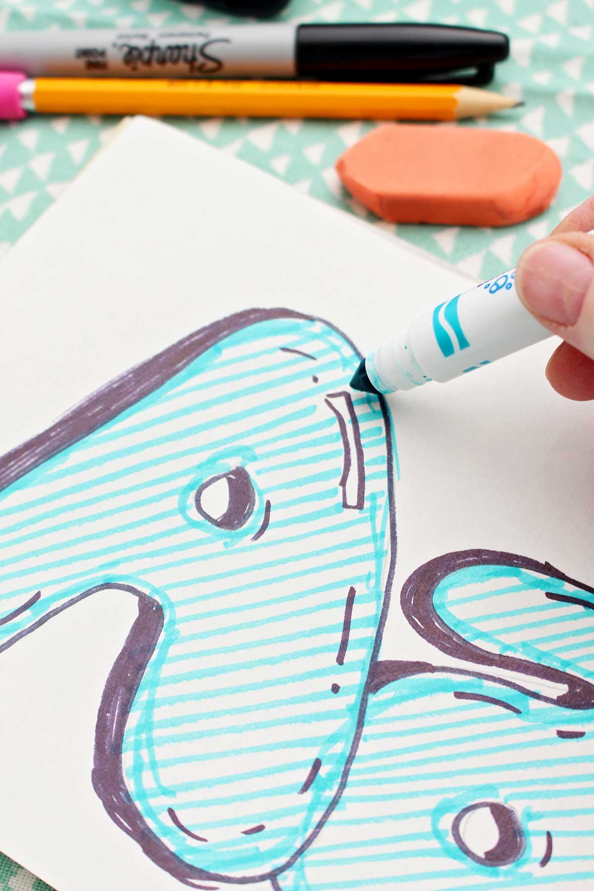 A close up of the uppercase "a" being colored in with blue marker.