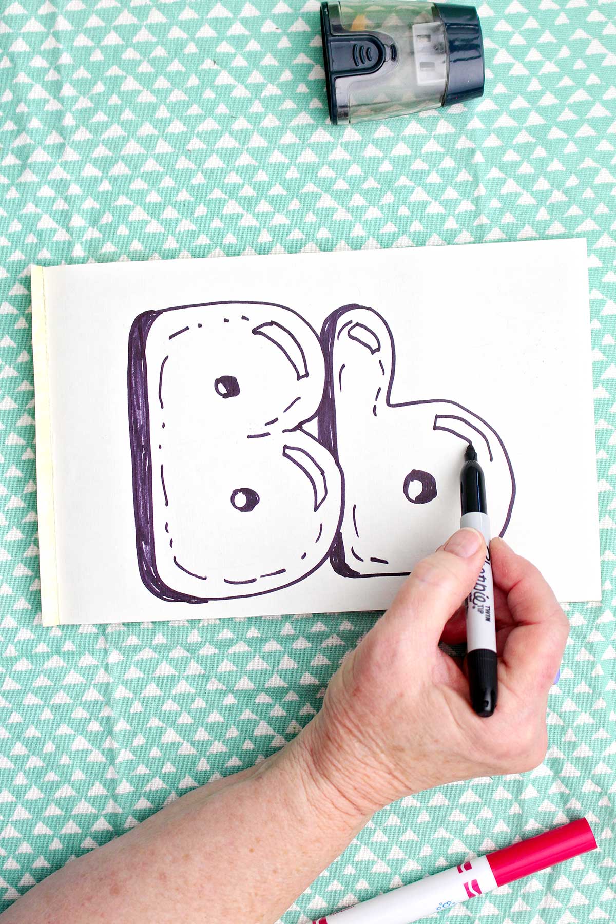 A person adding detail to a lowercase bubble letter "b with a sharpie marker.