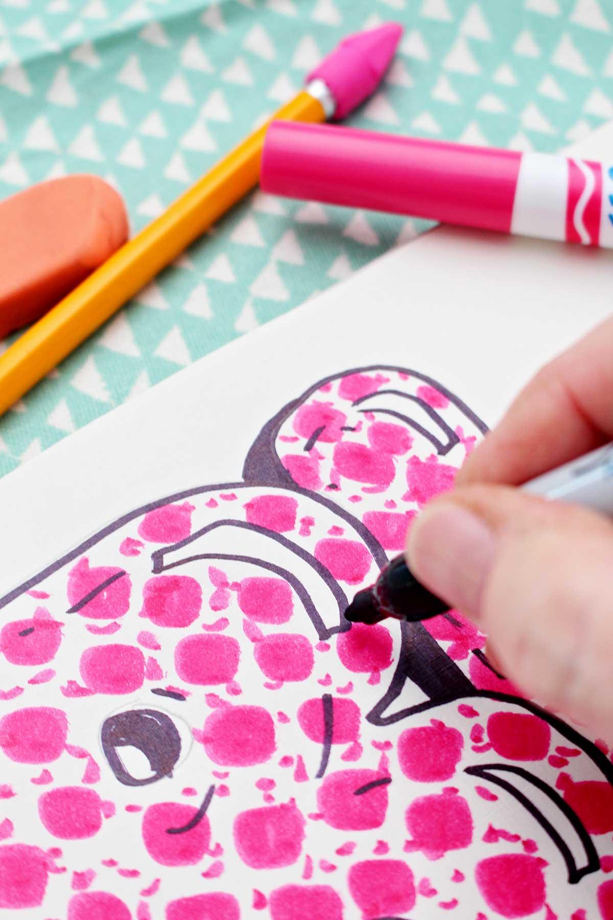 A close up of a person adding detail to a colored in bubble letter "b".