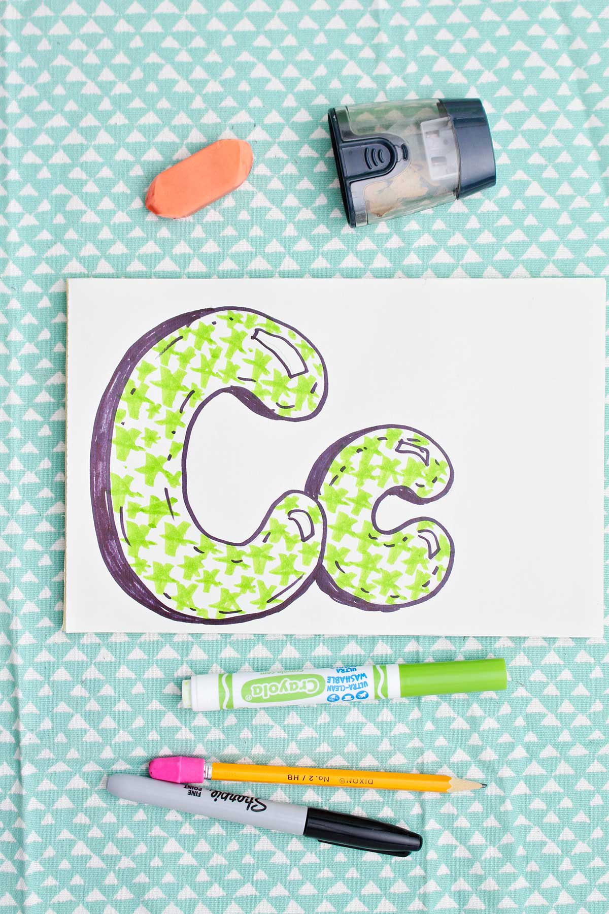 Bubble letter "C" in upper and lowercase shadowed in sharpie and colored in with light green marker star pattern.