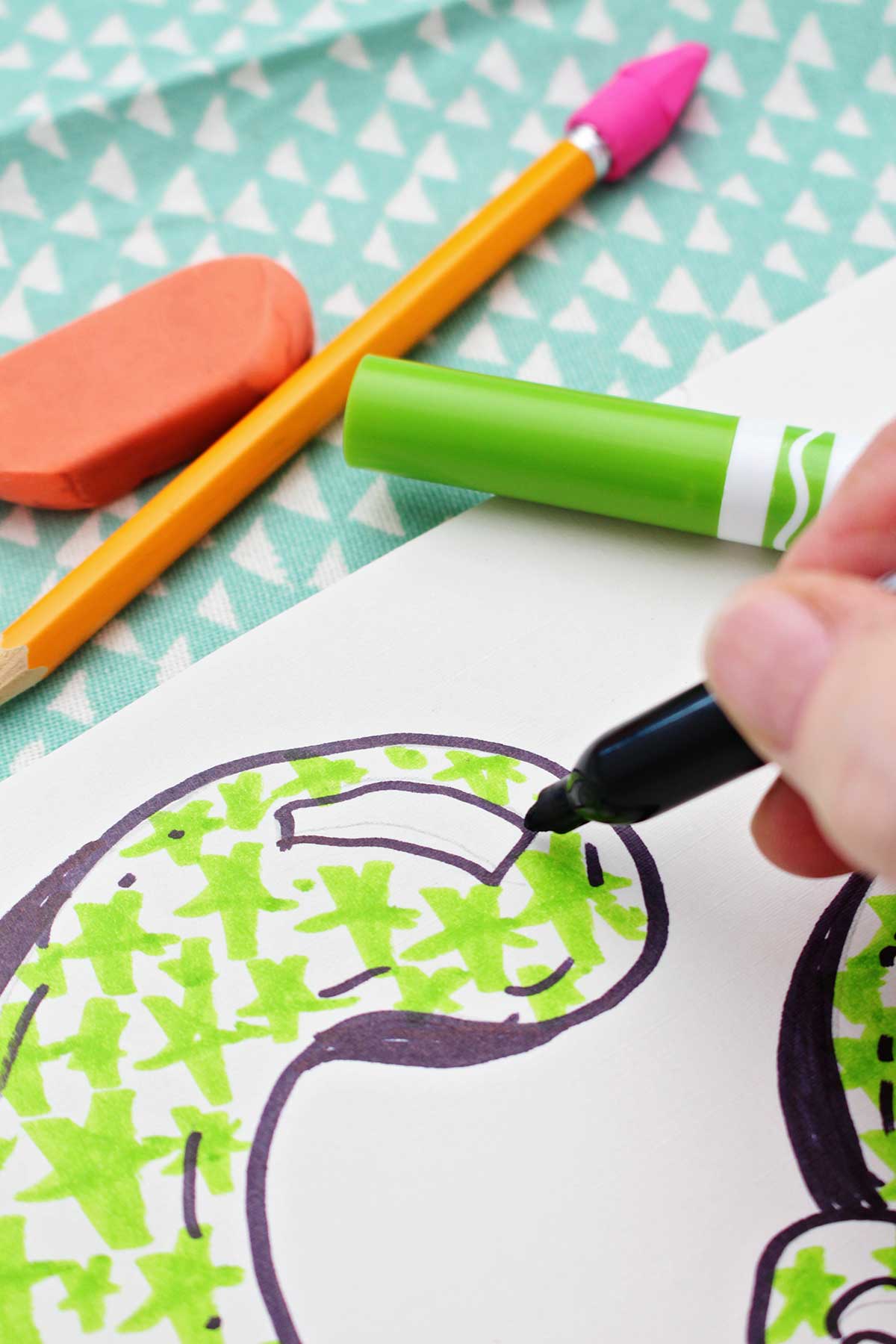 A close up of a person adding detail to a colored in bubble letter "c".