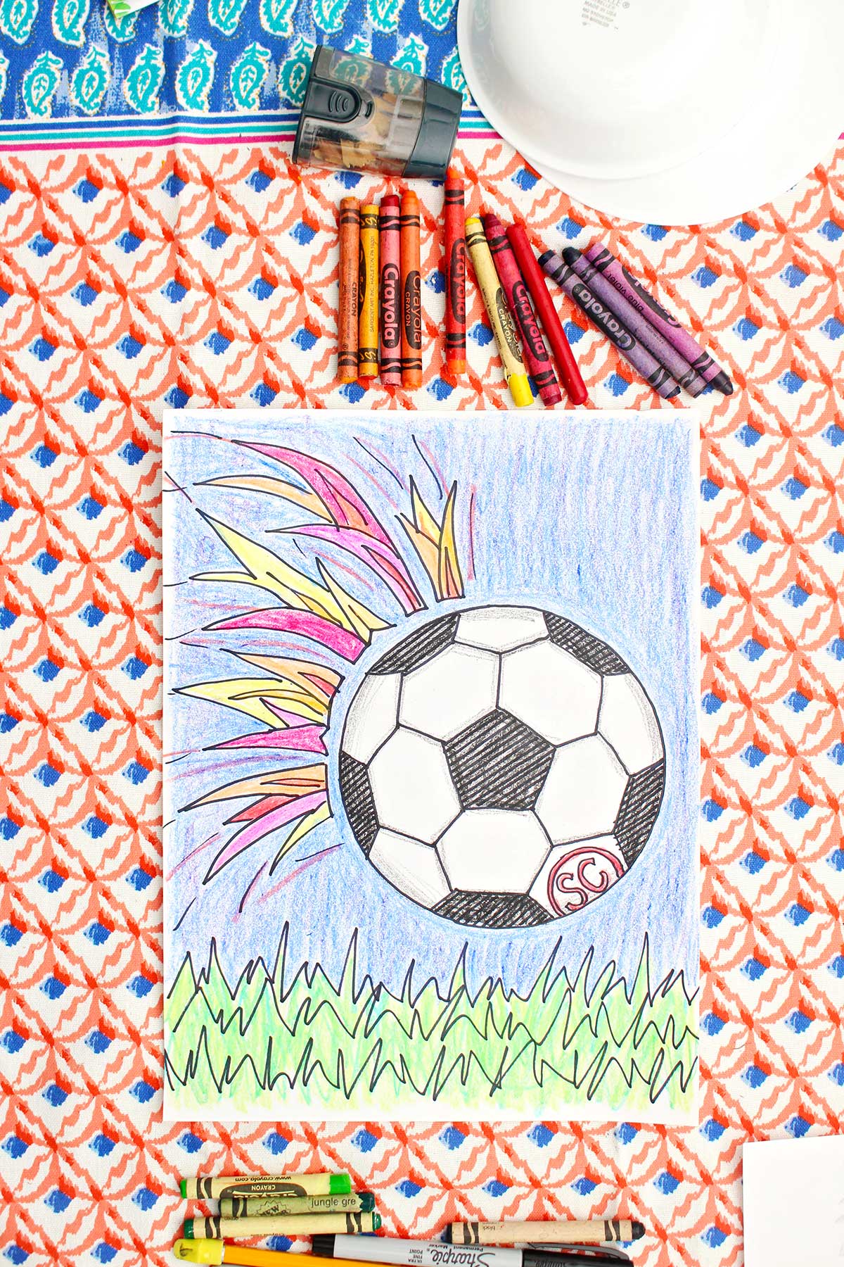 A colored in drawing of a soccer ball flying towards the grass with colorful flames behind it.