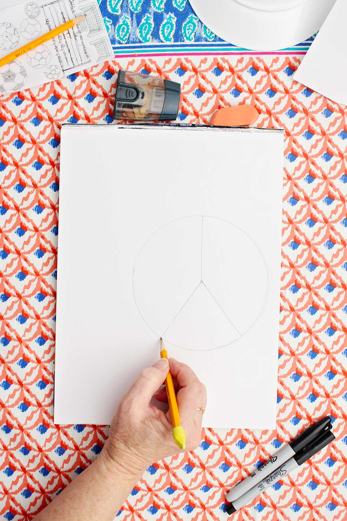 A person dividing a pencil drawing of a circle into three parts.