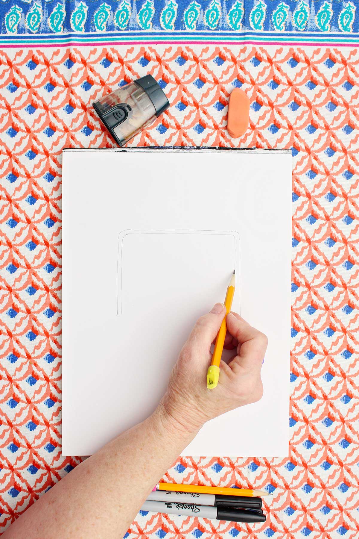 Person sketching a picture of a soccer goal with pencil.