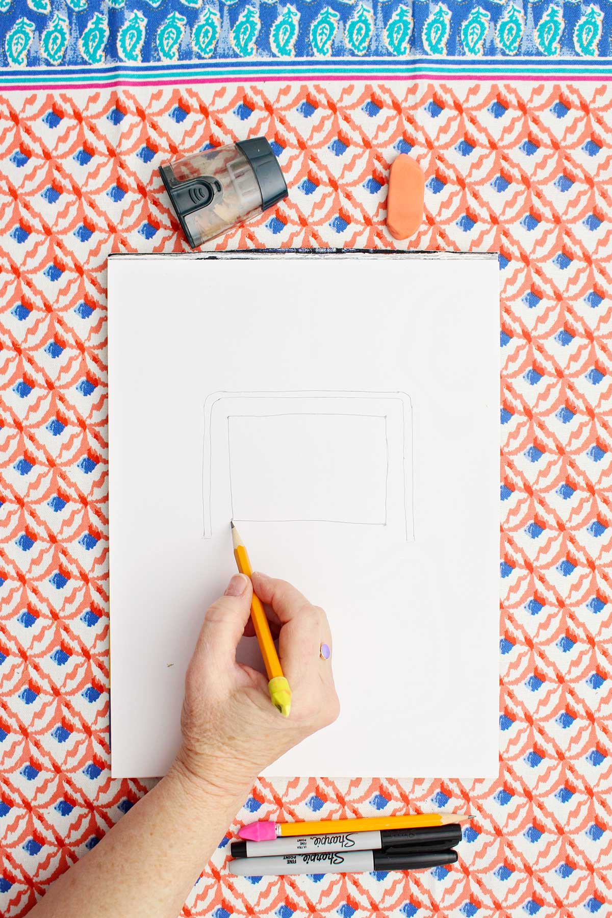 Person sketching a picture of a soccer goal with pencil.