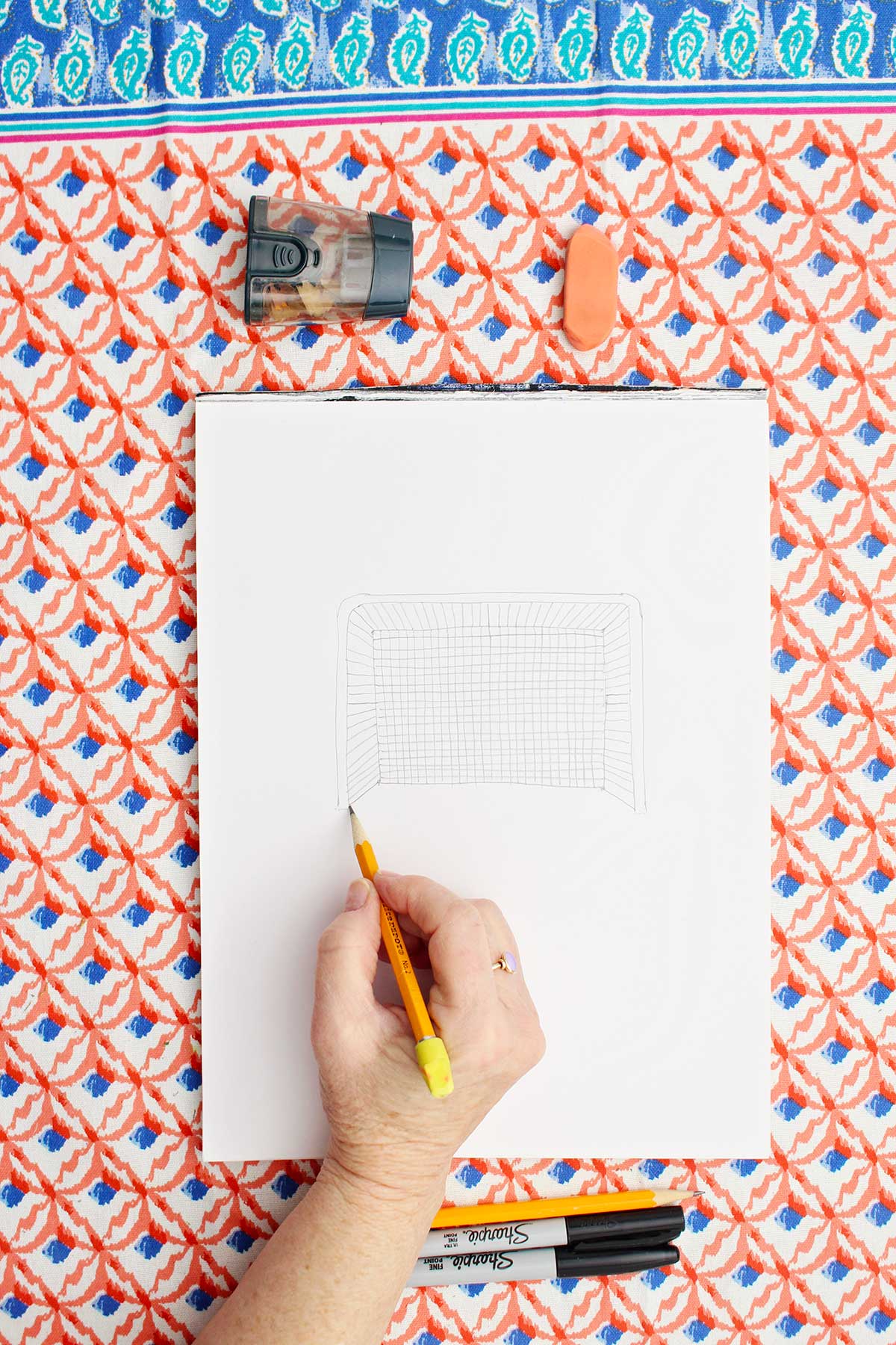 Person sketching a picture of a soccer goal with pencil.