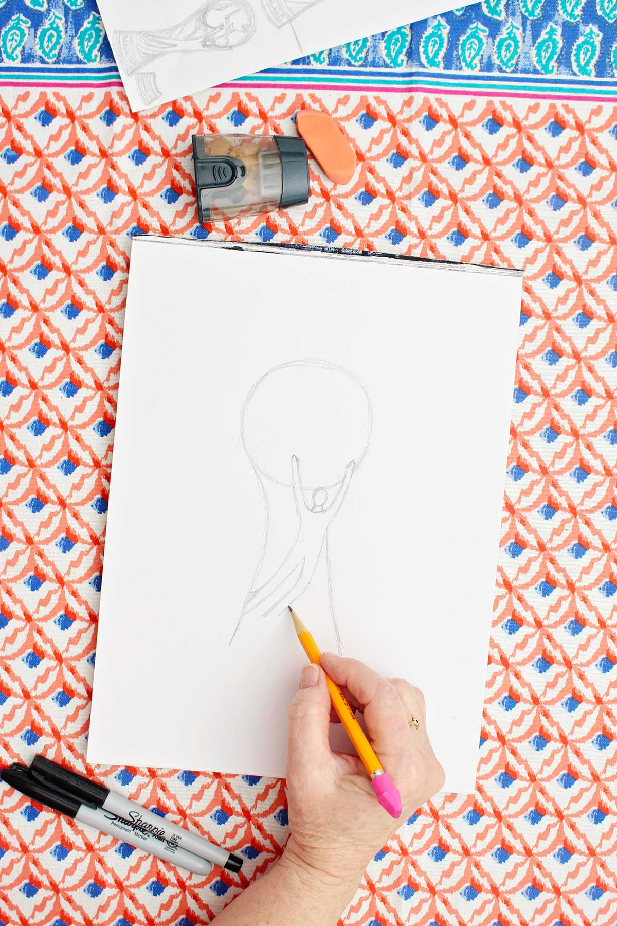 A person sketching the legs of a person on a FIFA World Cup trophy.