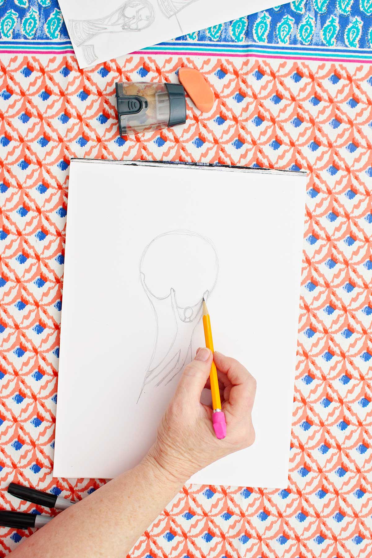 Person sketching hands on a person who is holding the ball on the FIFA World Cup Trophy.