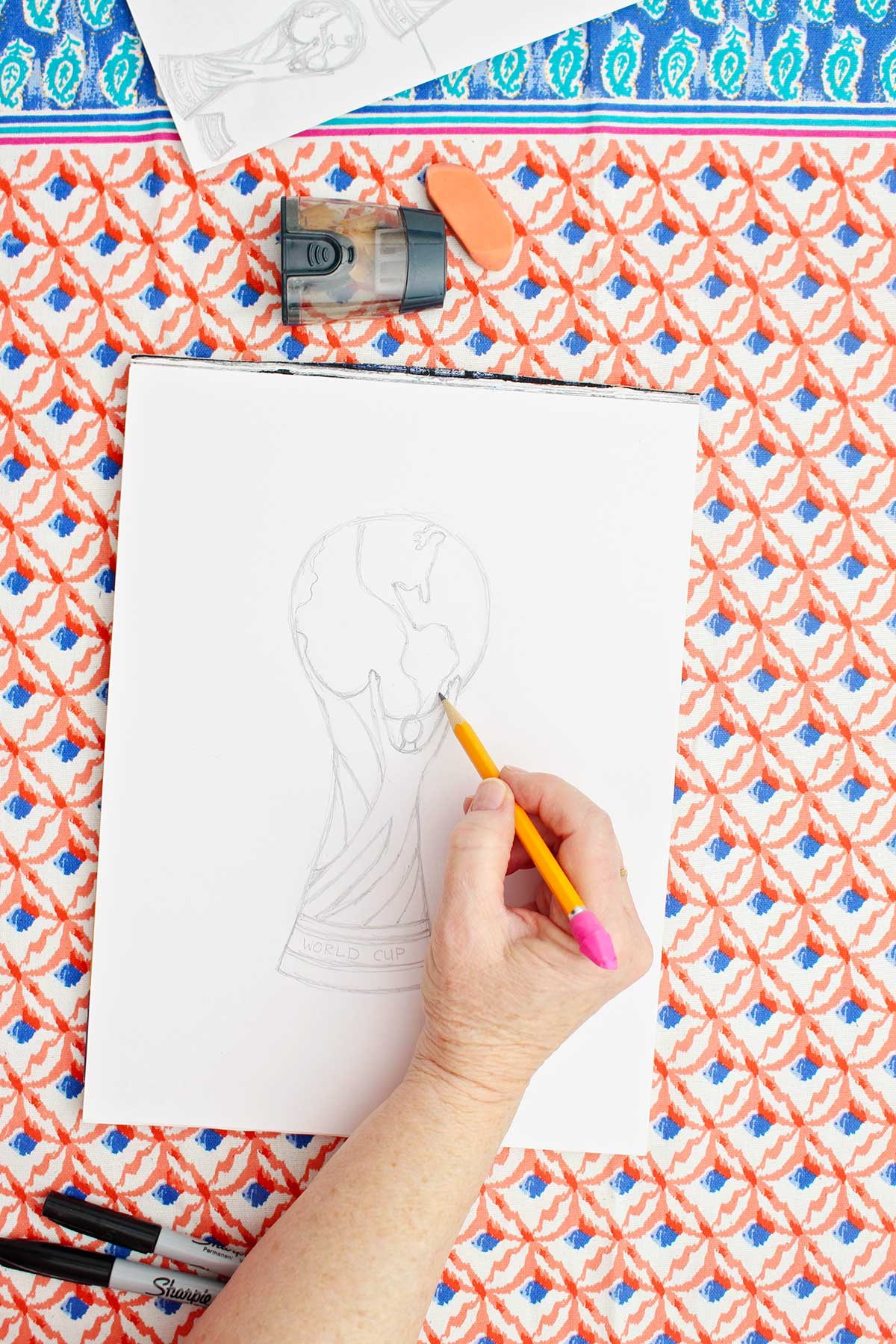 A person fishing up a pencil sketch of the FIFA World Cup Trophy.