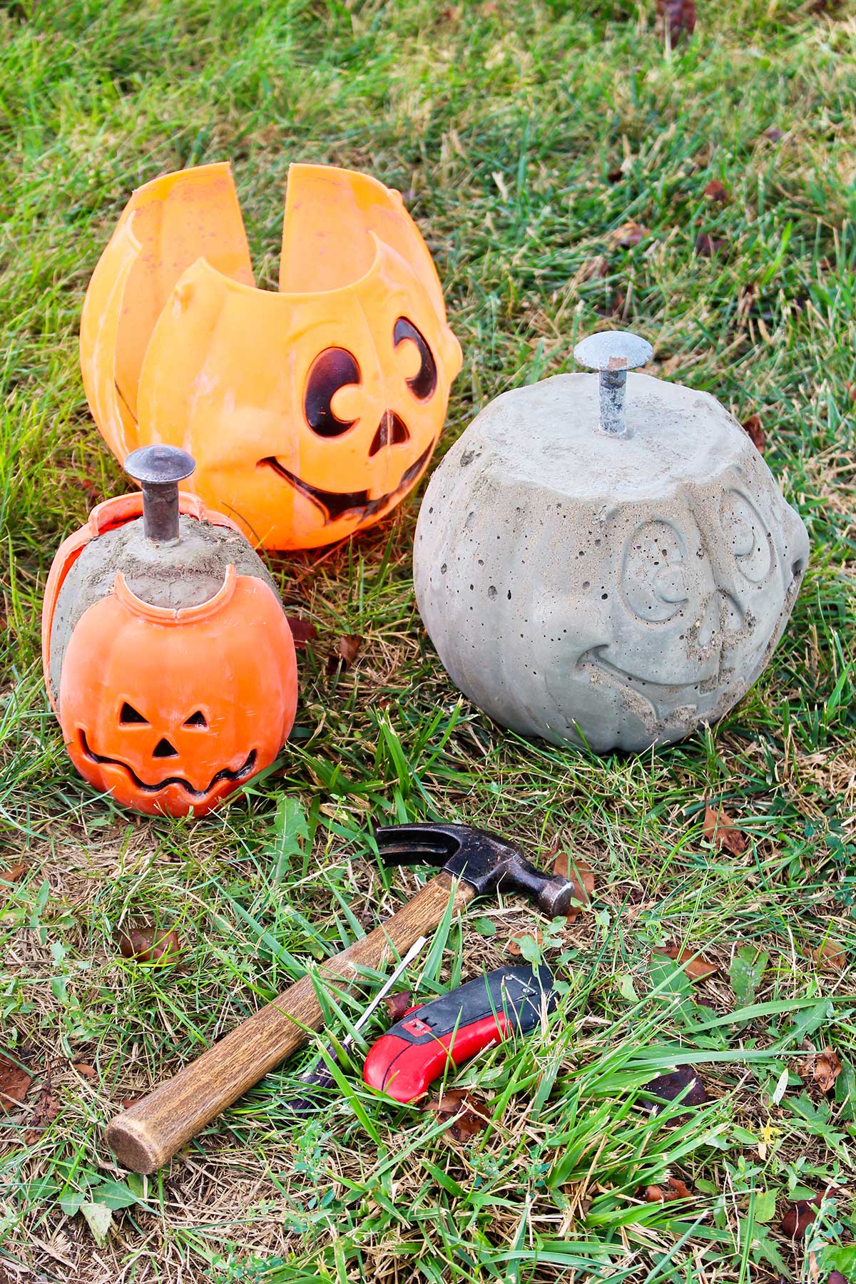 Finished DIY concrete pumpkins sitting next to their plastic shells on the grass.