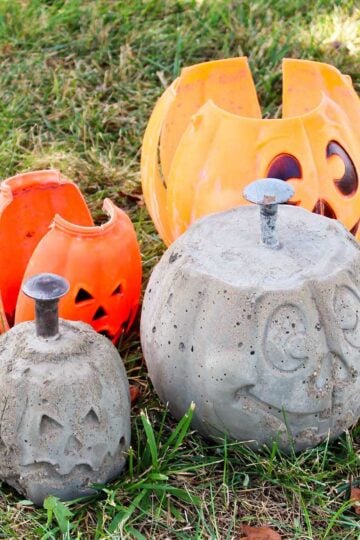 Finished DIY concrete pumpkins sitting next to their plastic shells on the grass.