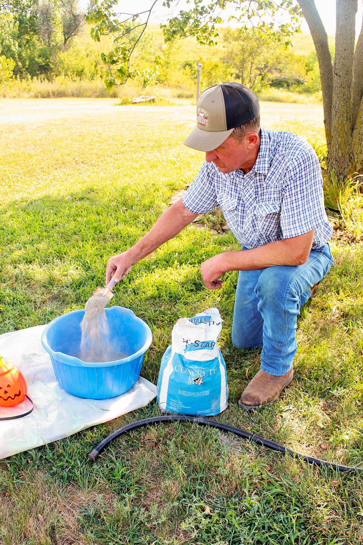 A man mixing concrete outside in a blue tub