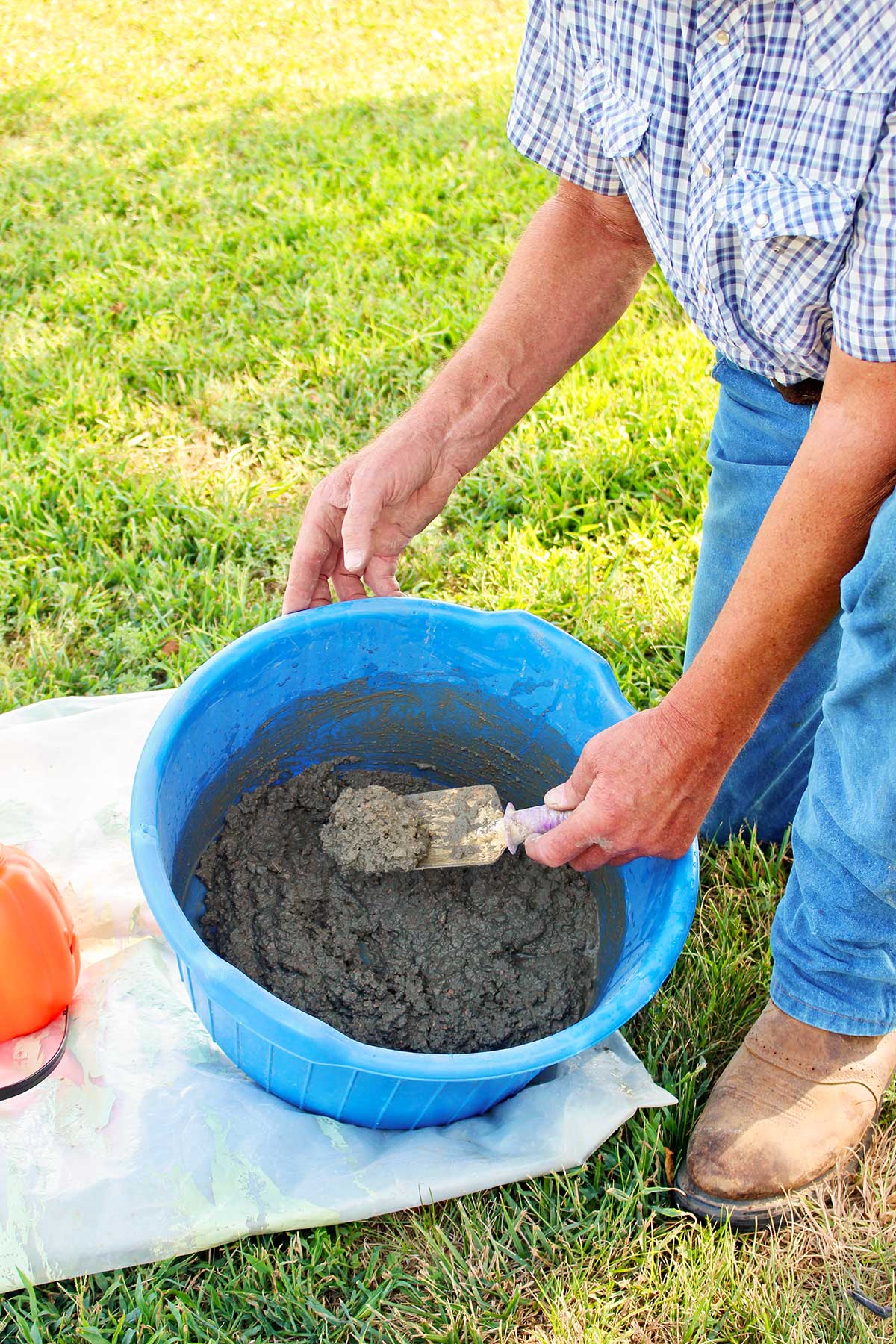 A man mixing concrete outside in a blue tub