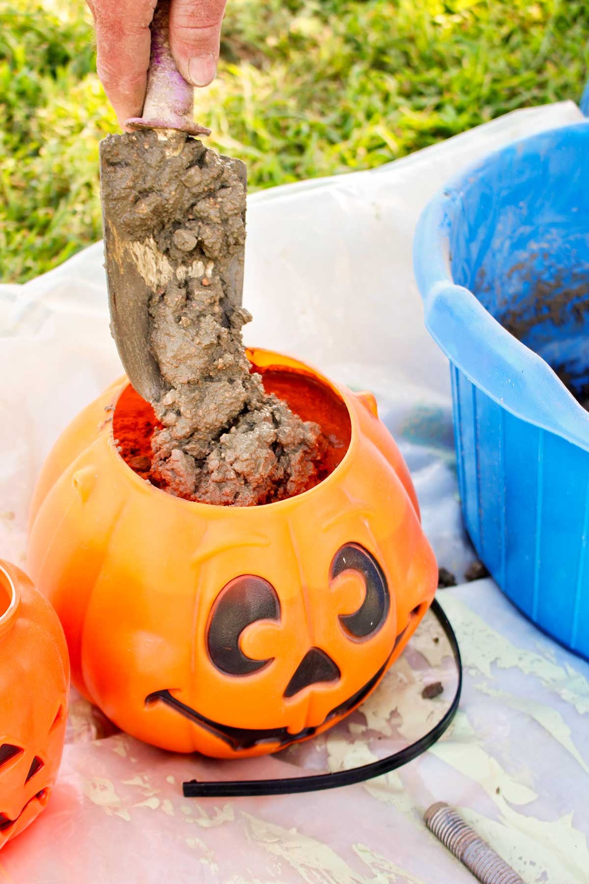 A shovel adding mixed concrete to a plastic pumpkin