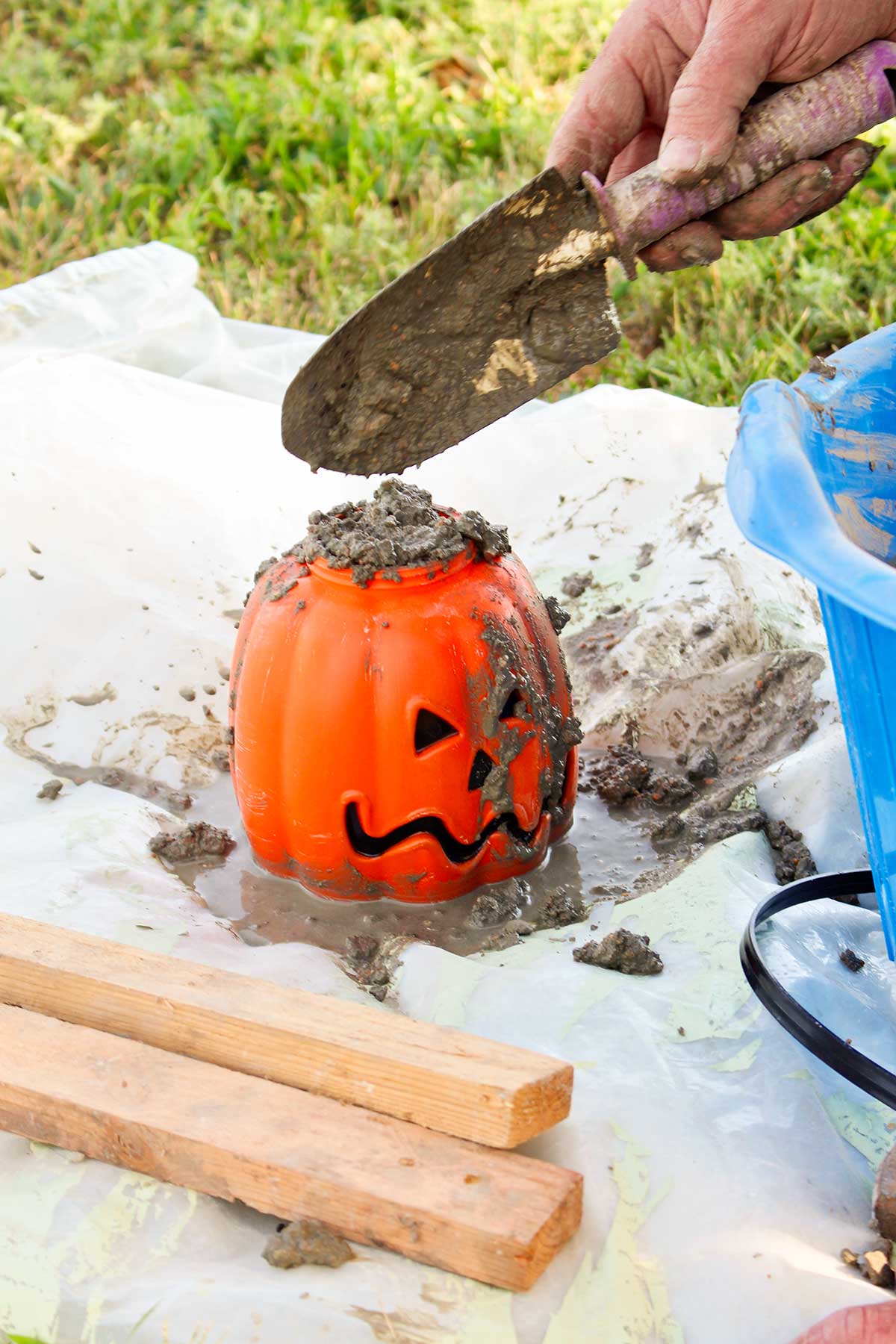 A shovel adding mixed concrete to a plastic pumpkin