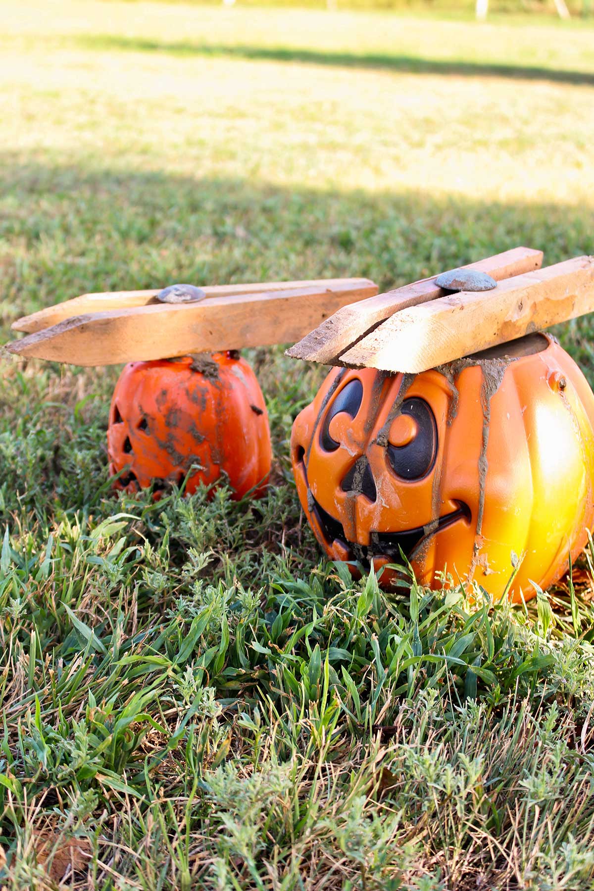 Two plastic pumpkins filled with concrete, with wood pieces holding a metal stem in place