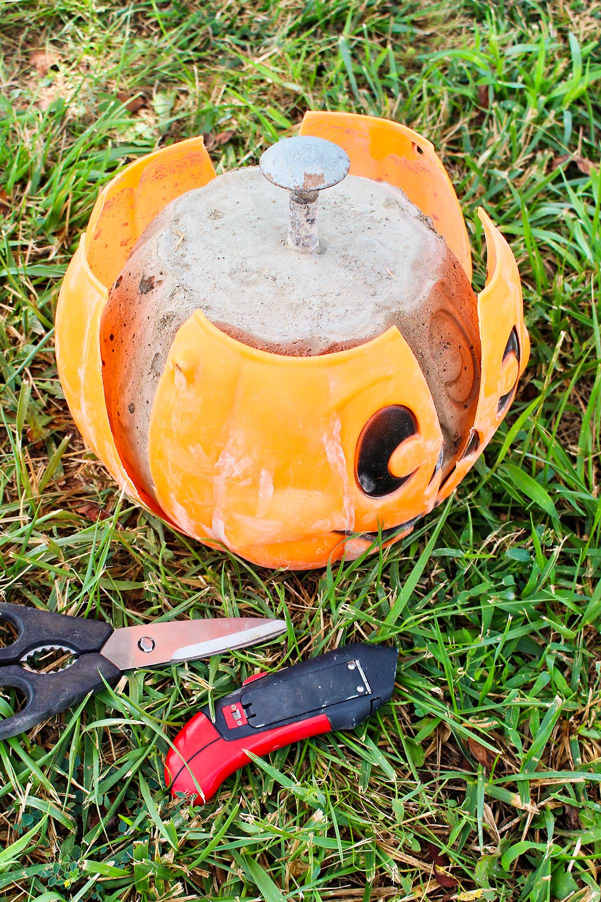 A concrete pumpkin in a plastic shell that has been cut down the sides