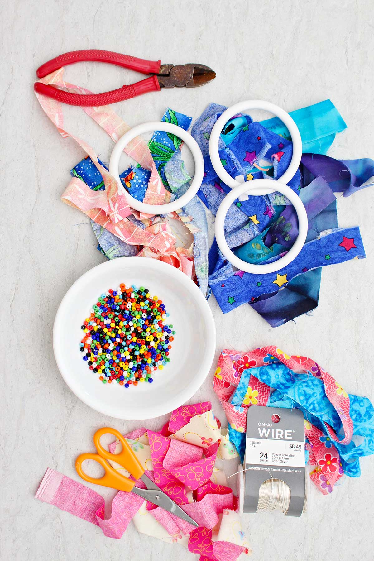 Colorful beads, strips of fabric, plastic bracelets, wire, wire cutters and scissors.