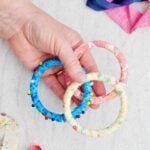 A person holding three colorful fabric BoHo bracelets, one with beads.