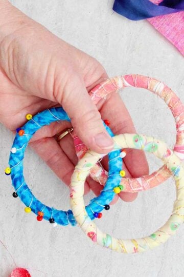 A person holding three colorful fabric BoHo bracelets, one with beads.