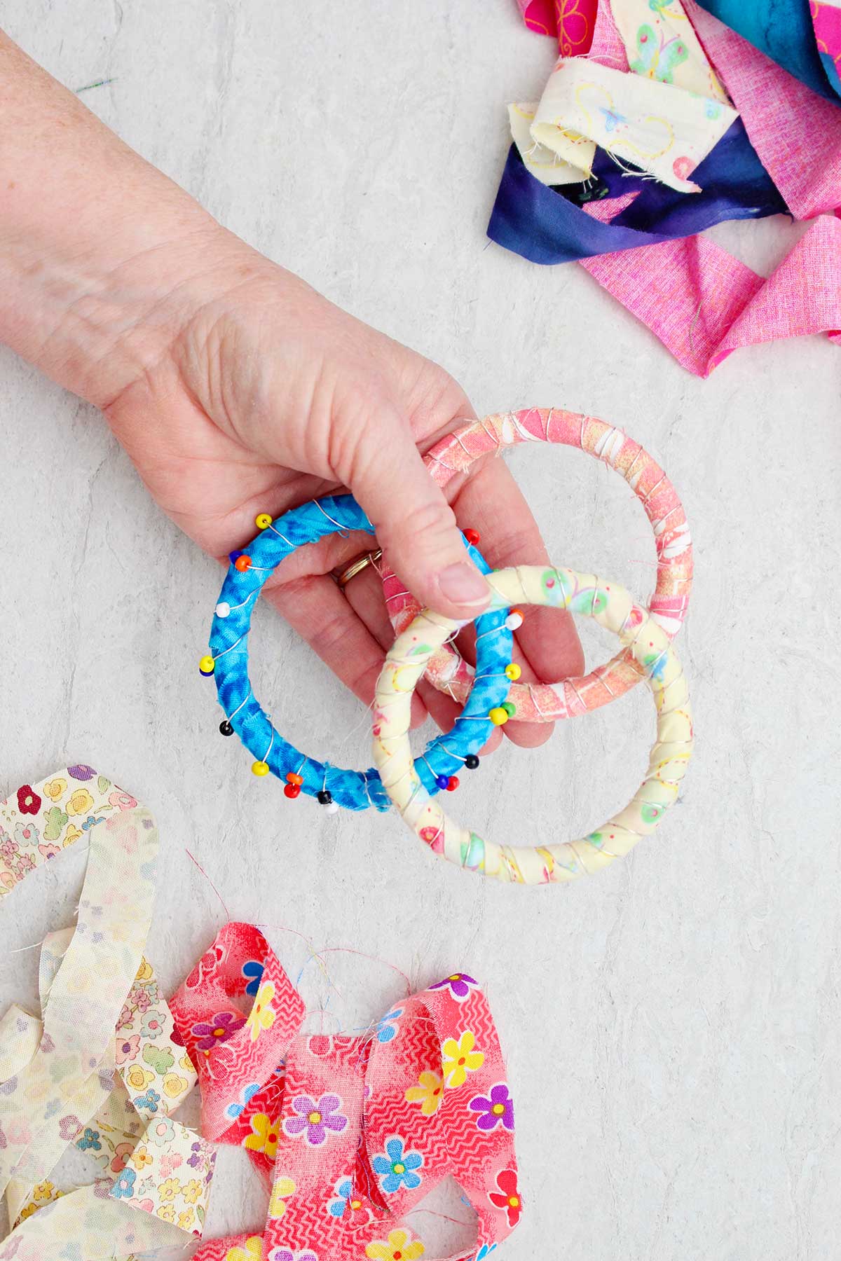 A person holding three colorful fabric BoHo bracelets, one with beads.