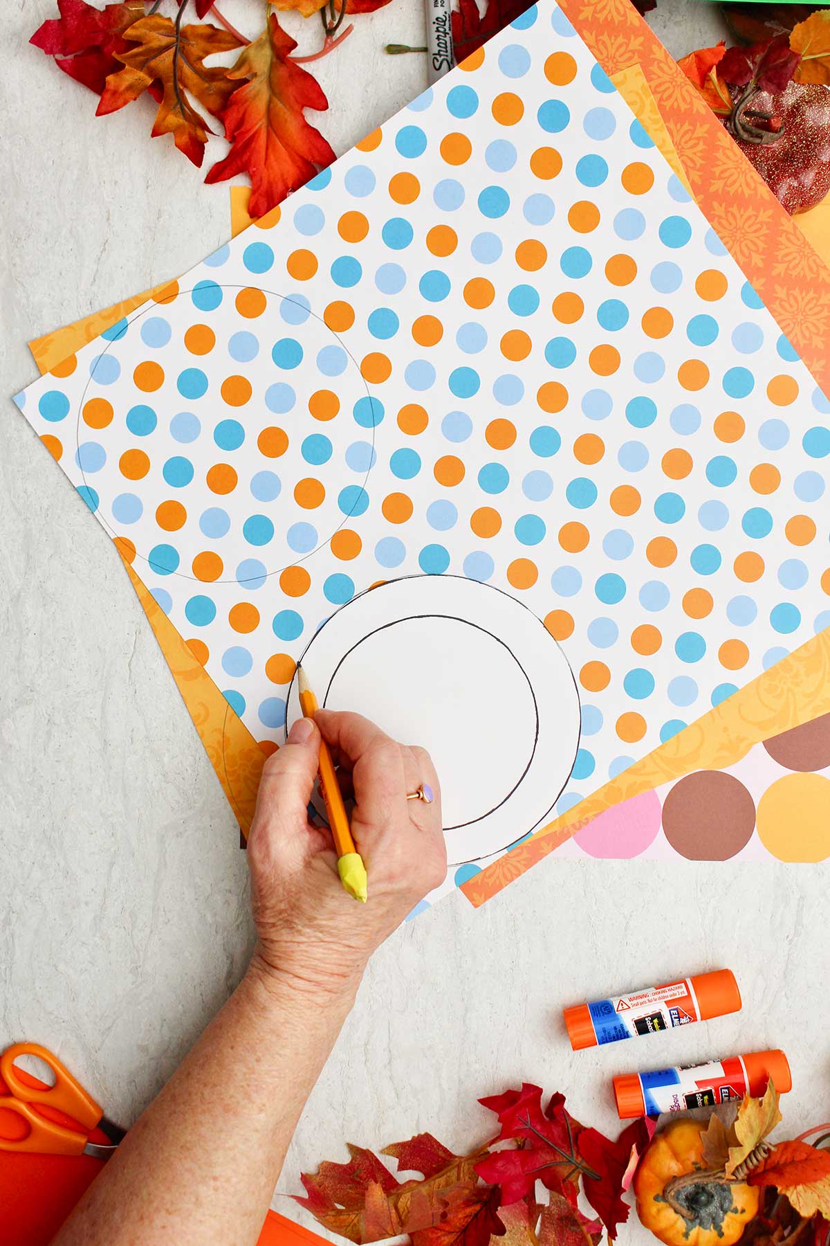 A person using a circular pattern to trace a circle on colorful patterned paper.