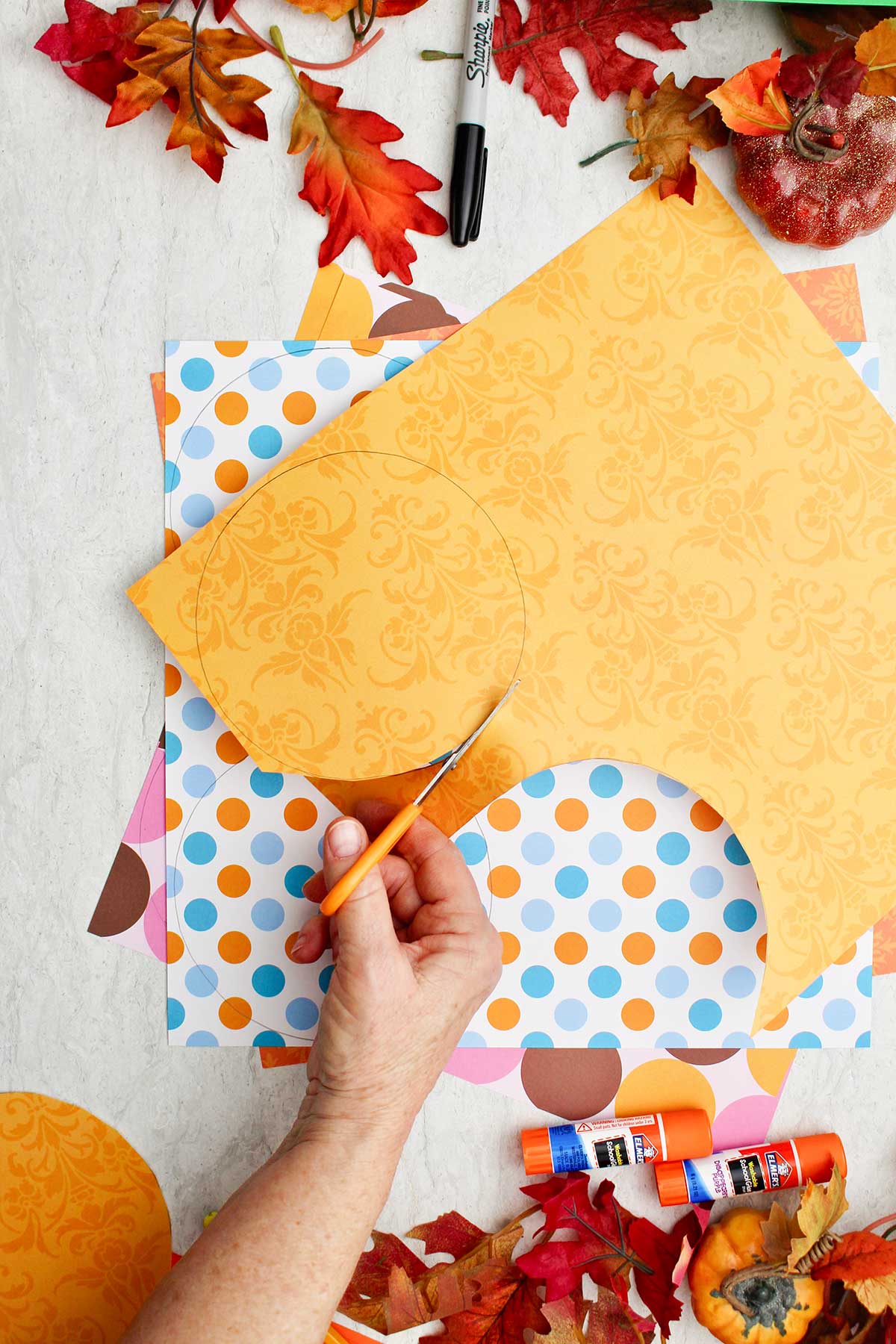 A person cutting circles out of colorful patterned paper.