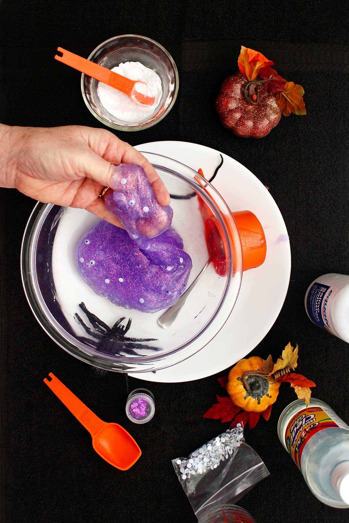 Person playing with Halloween slime in the glass bowl.