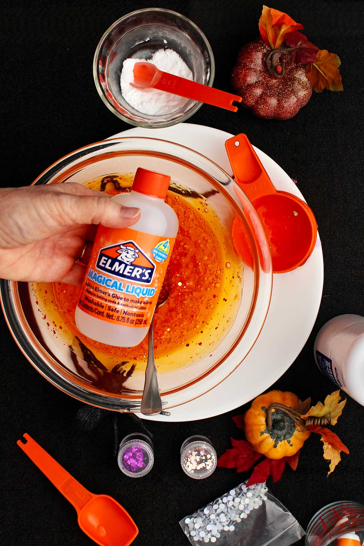 Person about to add Elmer's Magical Liquid in their orange slime recipe.