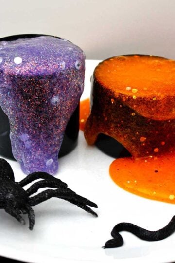 Two different spooky glittery slime recipes spilling out of their black containers with a fake spider near by.