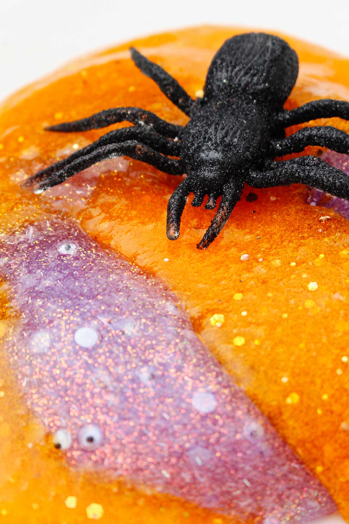 A close up view of the orange and purple slime with a fake spider resting on top.