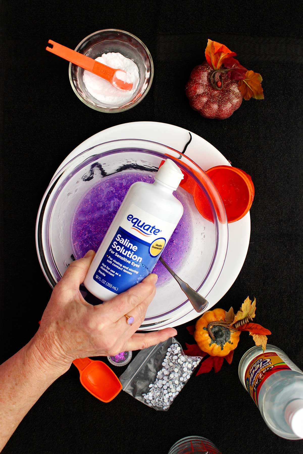 Person about do add some saline solution to their purple glittery slime.